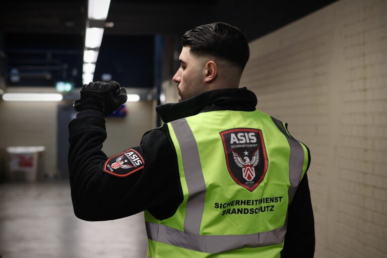 ASIS Sicherheitsdienst-Mitarbeiter im Objektschutz mit Funkgerät in einer Überwachungshaltung