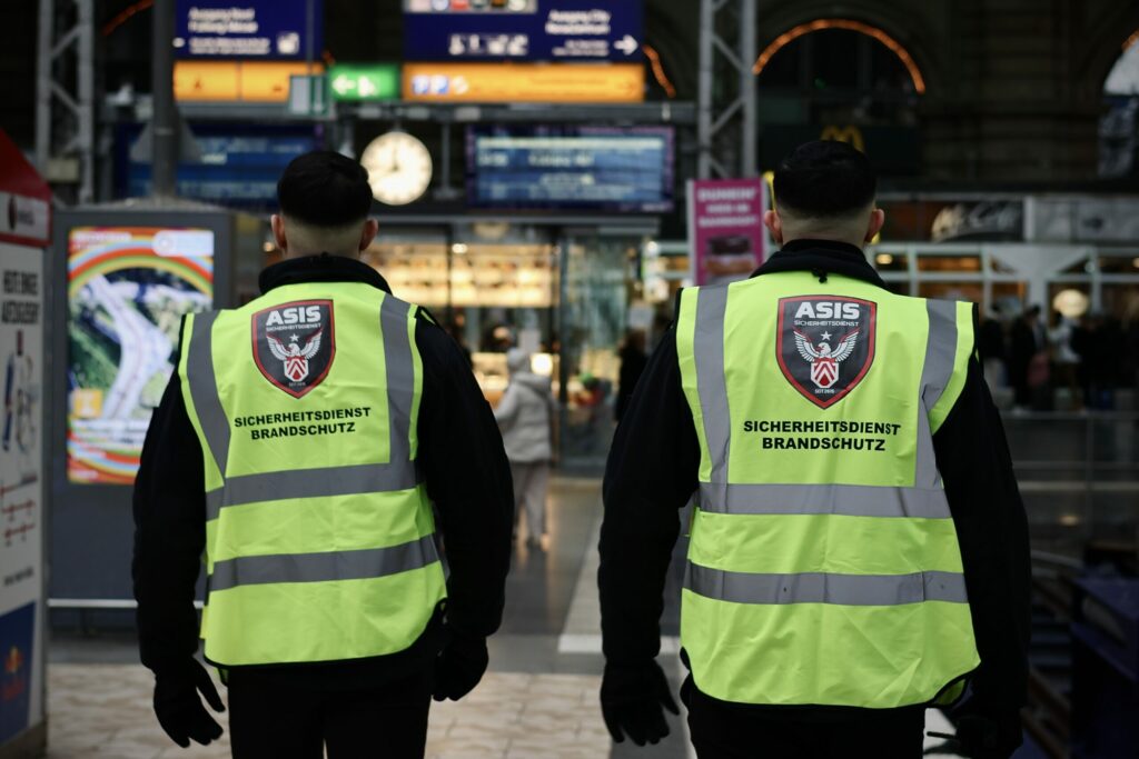 Zwei Sicherheitsmitarbeiter von ASIS patrouillieren in einer Bahnhofshalle als Teil ihres Objektschutzdienstes