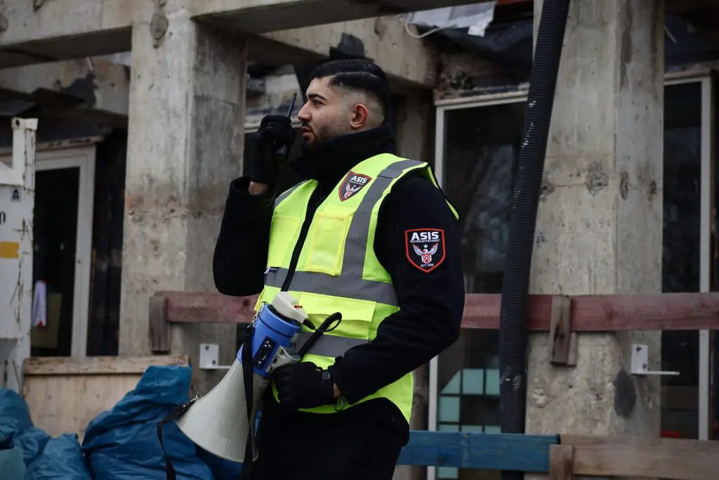 ASIS Sicherheitsmitarbeiter auf einer Baustelle kommuniziert über Funkgerät für schnelle Reaktion und Berichterstattung