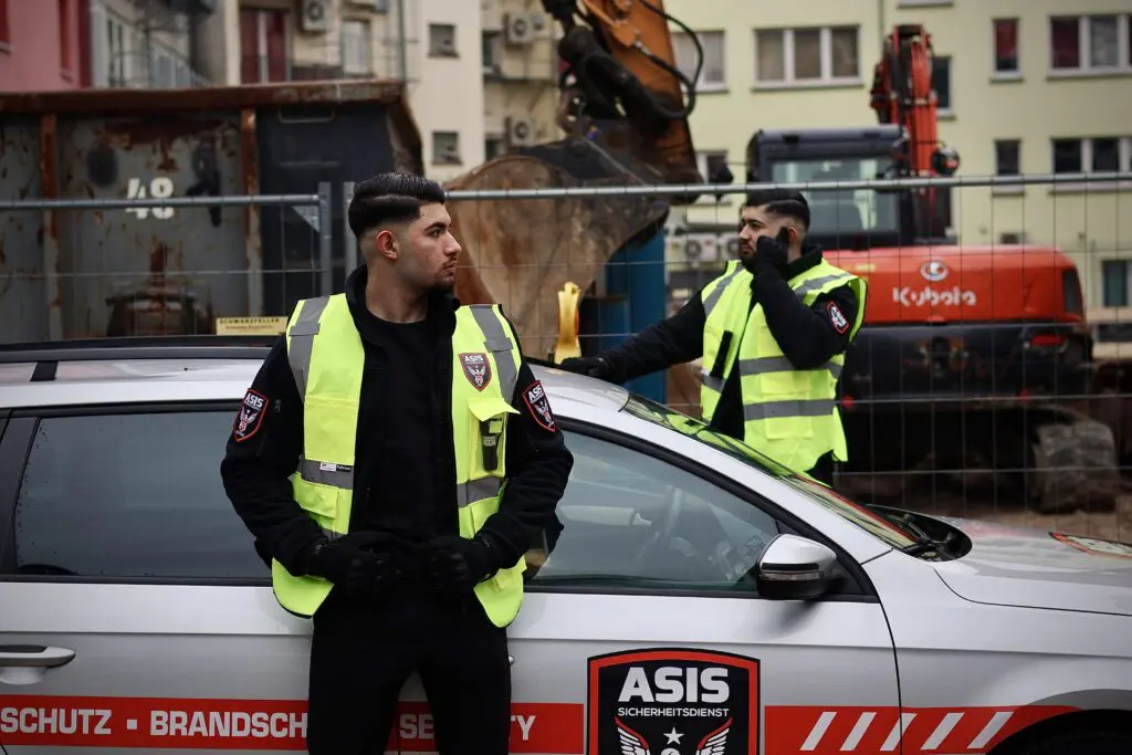 Zwei ASIS Sicherheitsmitarbeiter überwachen eine aktive Baustelle zur Gewährleistung der kontinuierlichen Sicherheit